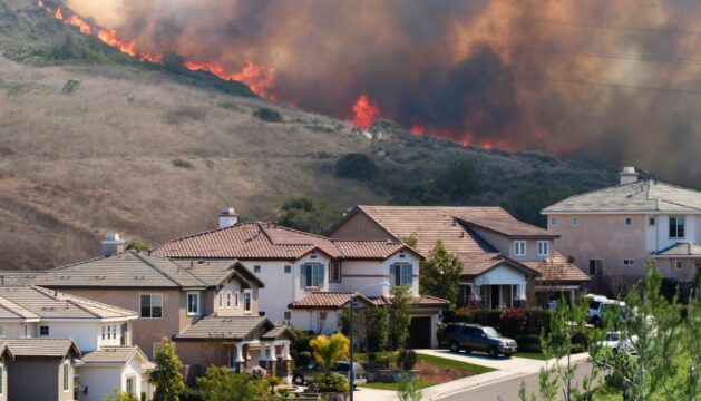 A wildfire burning near homes.